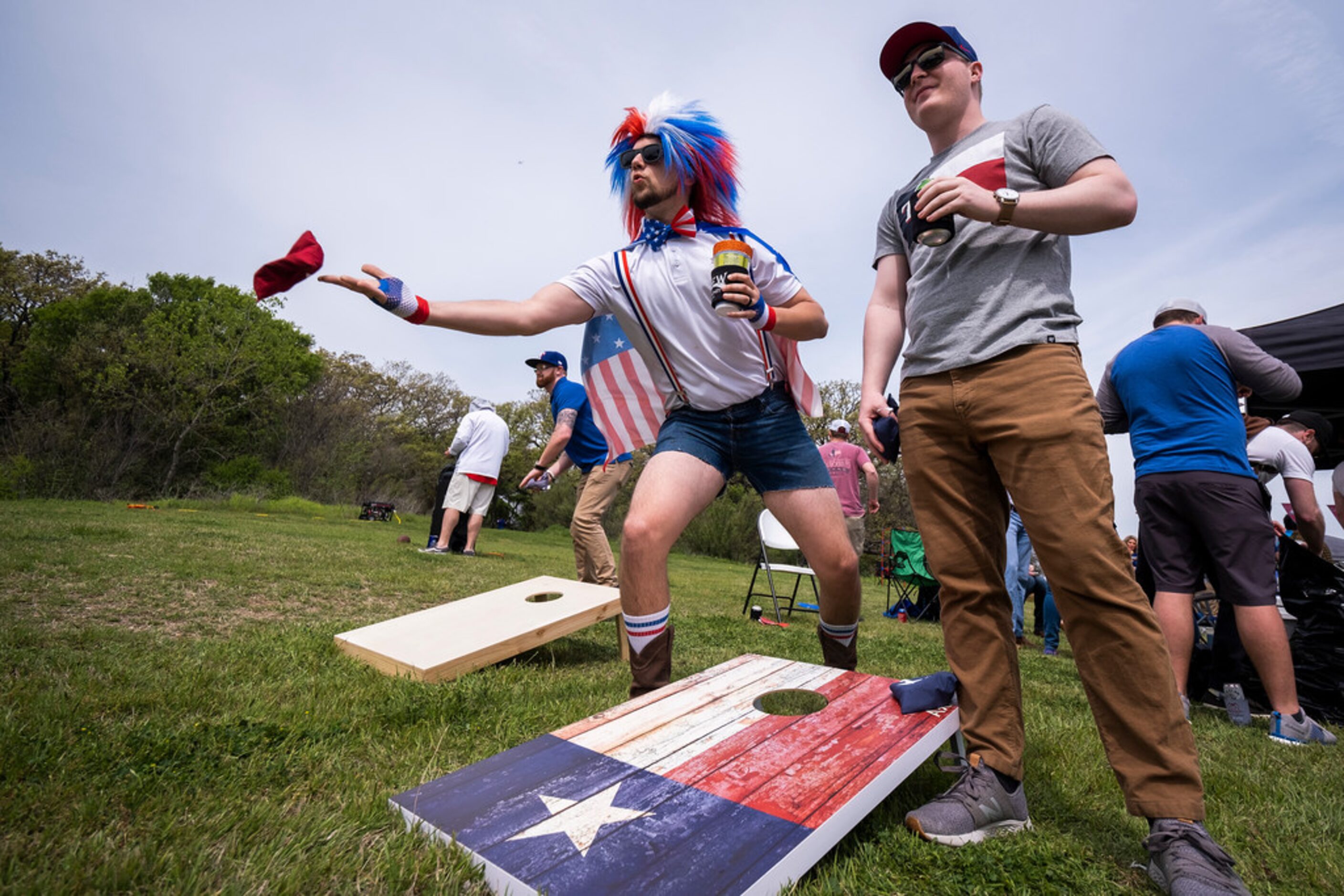 Fans Clayton Ferrell (center) and Ryan Handy (right) play cornhole as they tailgate before...