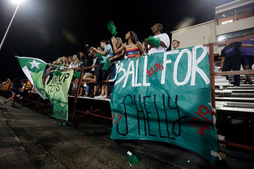 Arlington high school students cheer during the first half of their high school football...