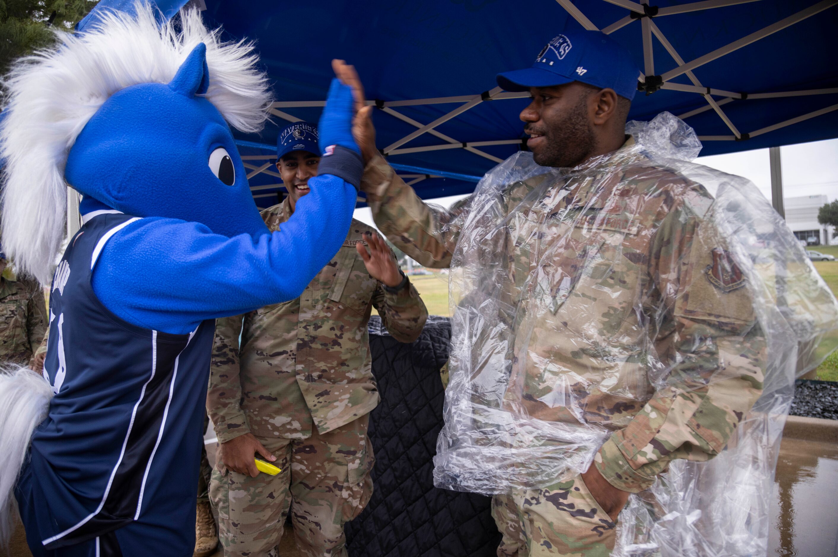 Champ, the Dallas Mavericks mascot, high-fives Technical Sergeant (TSgt) Ibrahim Barry with...