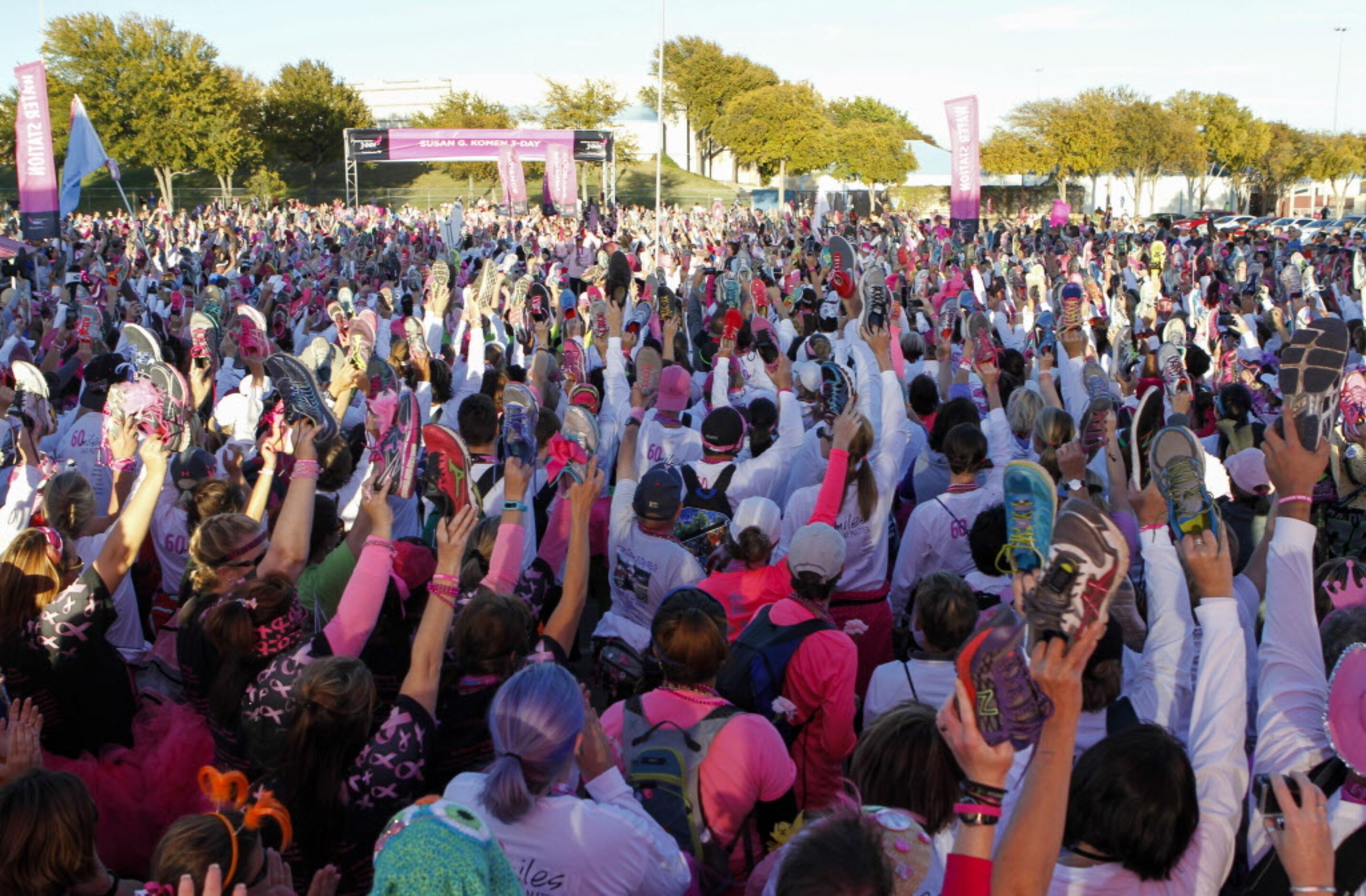 Walkers hold up their shoes in a salute to breast cancer survivors during the closing...