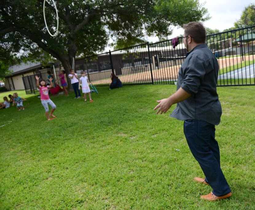 
Pastor Leonid Regheta throws a hula hoop to Anya Malamis, 7, during summer camp at River of...