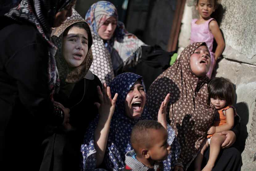 Palestinian relatives of four boys from the same extended Bakr family, grieve during their...