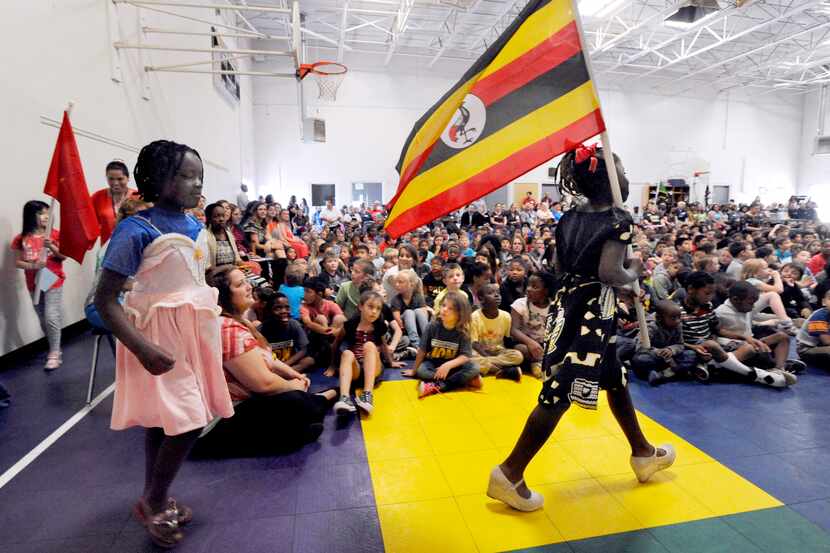 Third-grader Winner Moligi carries the flag of Uganda during a special assembly celebrating...