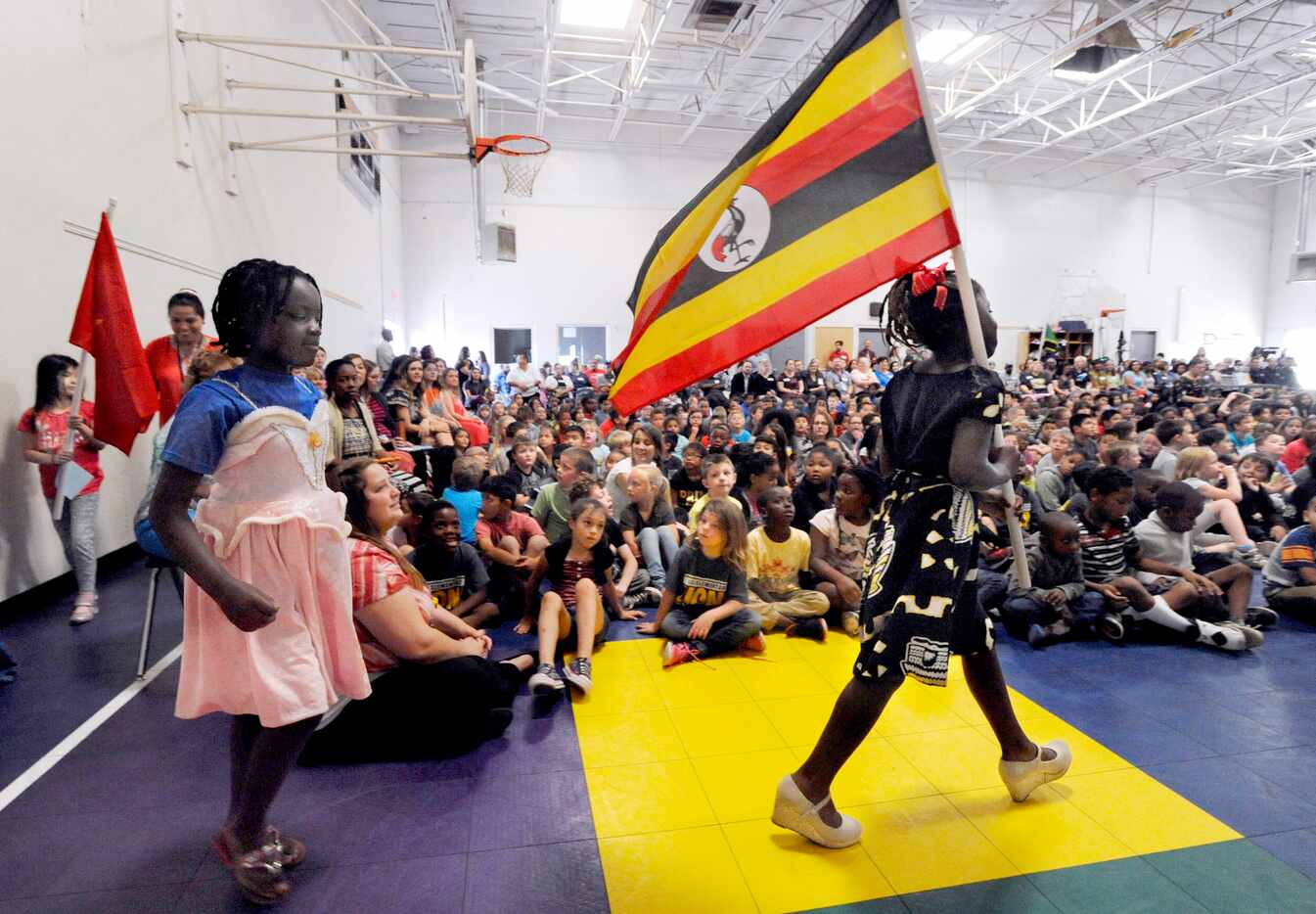Third-grader Winner Moligi carries the flag of Uganda during a special assembly celebrating...