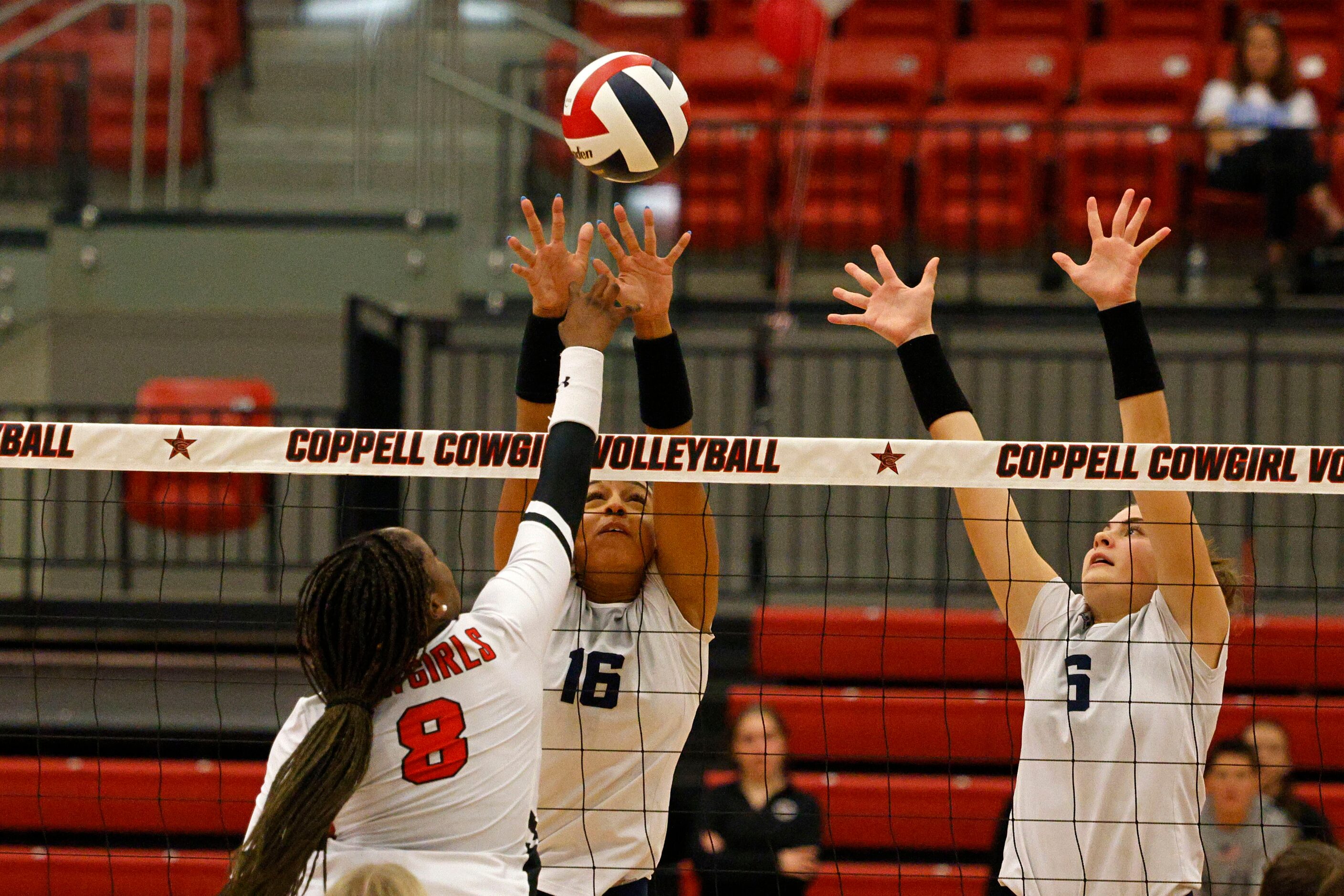 Coppell's Daki Kahungu (8) spikes the ball as Flower Mound's Geli St. Laurent (16) and...