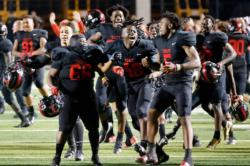 Euless Trinity football players celebrate their 27-24 overtime win against Hurst L.D. Bell...