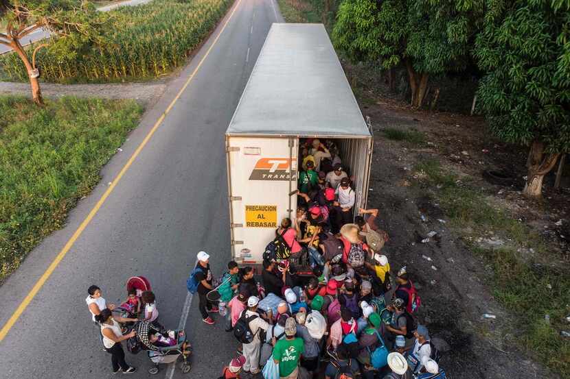 Honduran migrants taking part in a caravan heading to the United States get on a truck, near...