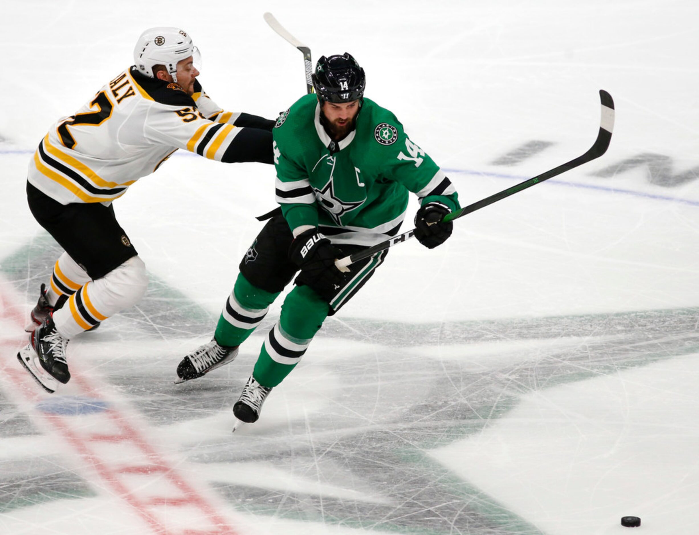 Dallas Stars left wing Jamie Benn (14) skates past Boston Bruins center Sean Kuraly (52)...