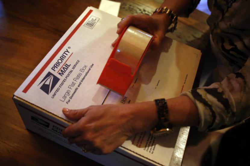Ginny Leone tapes up a box of goods during a "boxing club" get-together Tuesday, April 23,...