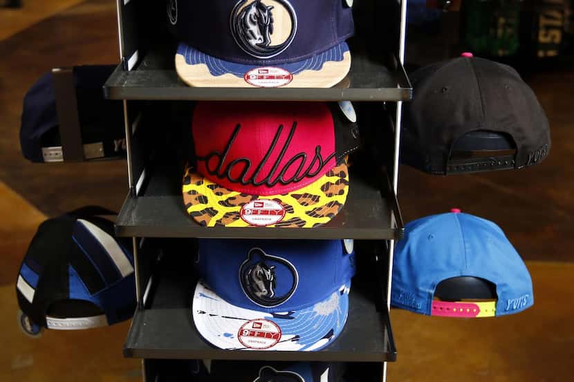 
Arlington-based Yums caps with the Mavs logo are sold at the fan shop. “We want as many...