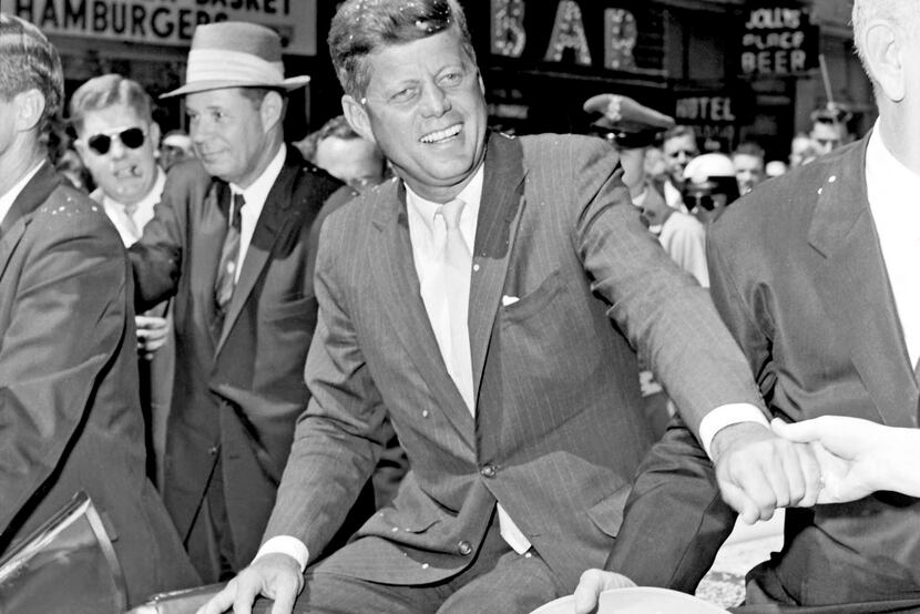On South Akard in downtown Dallas, John F. Kennedy reaches across Lyndon Johnson to greet an...
