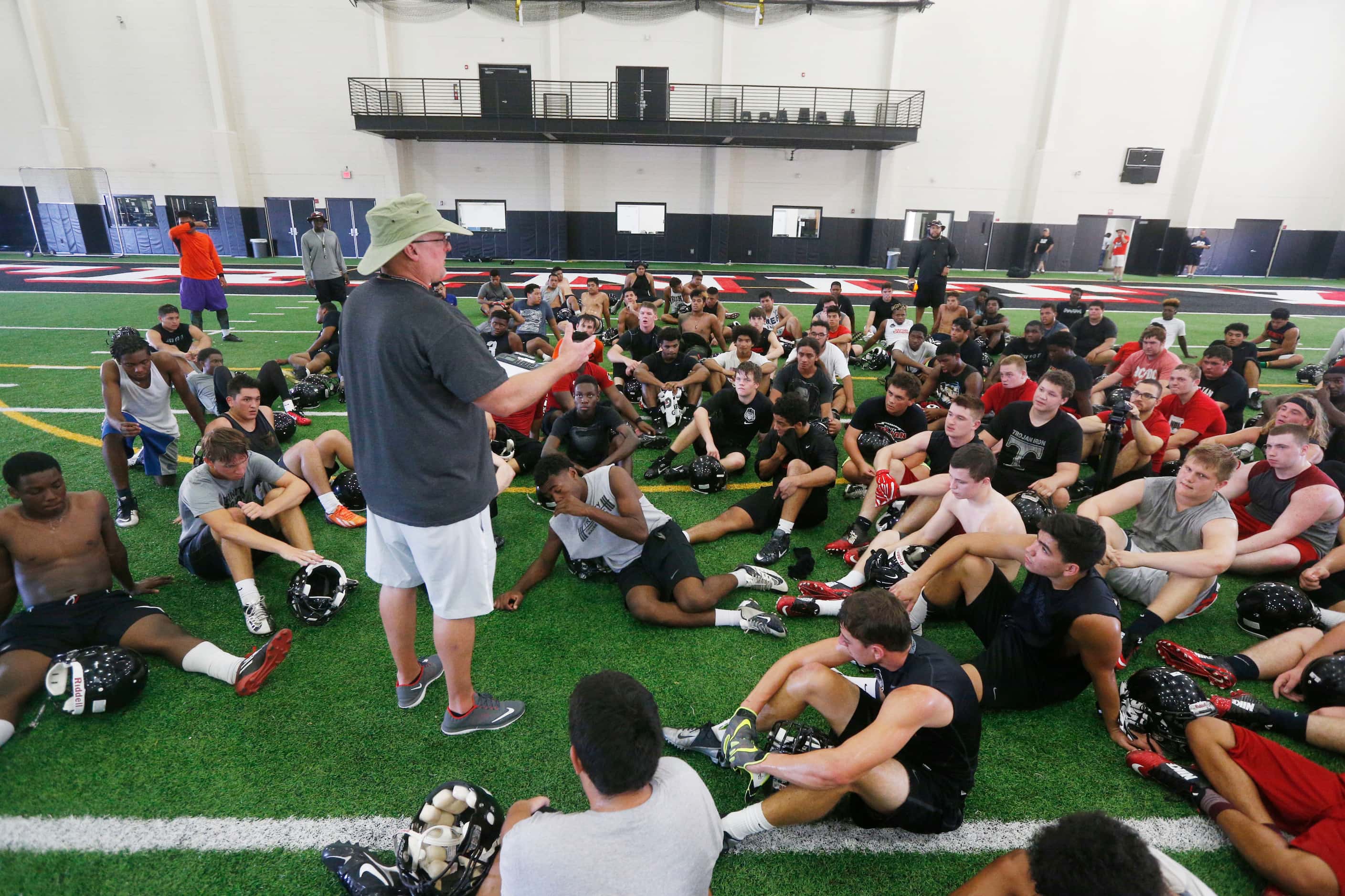 Coach Chris Jensen talks to his team after Euless Trinity's first day of football practice...