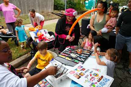 Cassandra Jackson paints the arm of Halston Miller, 5, and Carrie Ray makes balloon animals...