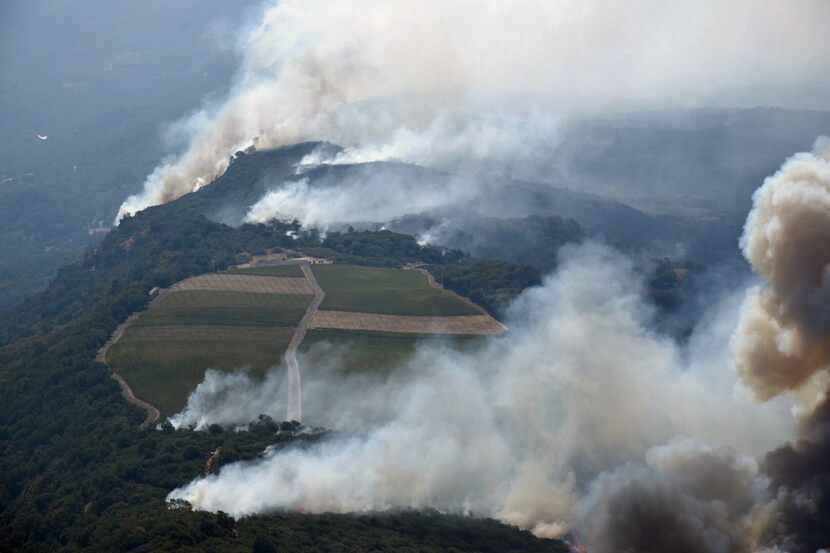 Smoke rises as a wildfire burns in the hills north east of Napa, Calif., Monday, Oct. 9,...
