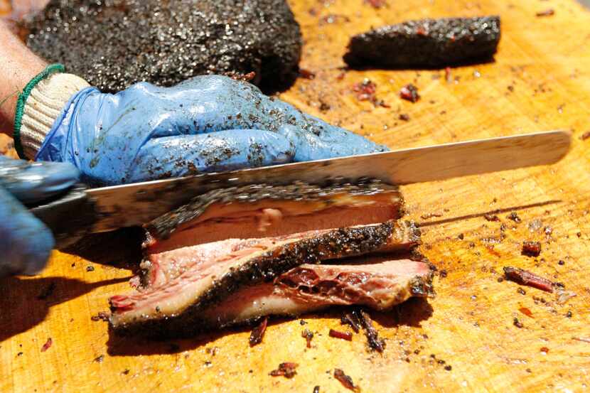 In this pre-pandemic photo, a worker at Cattleack Barbecue in Farmers Branch slices smoked...