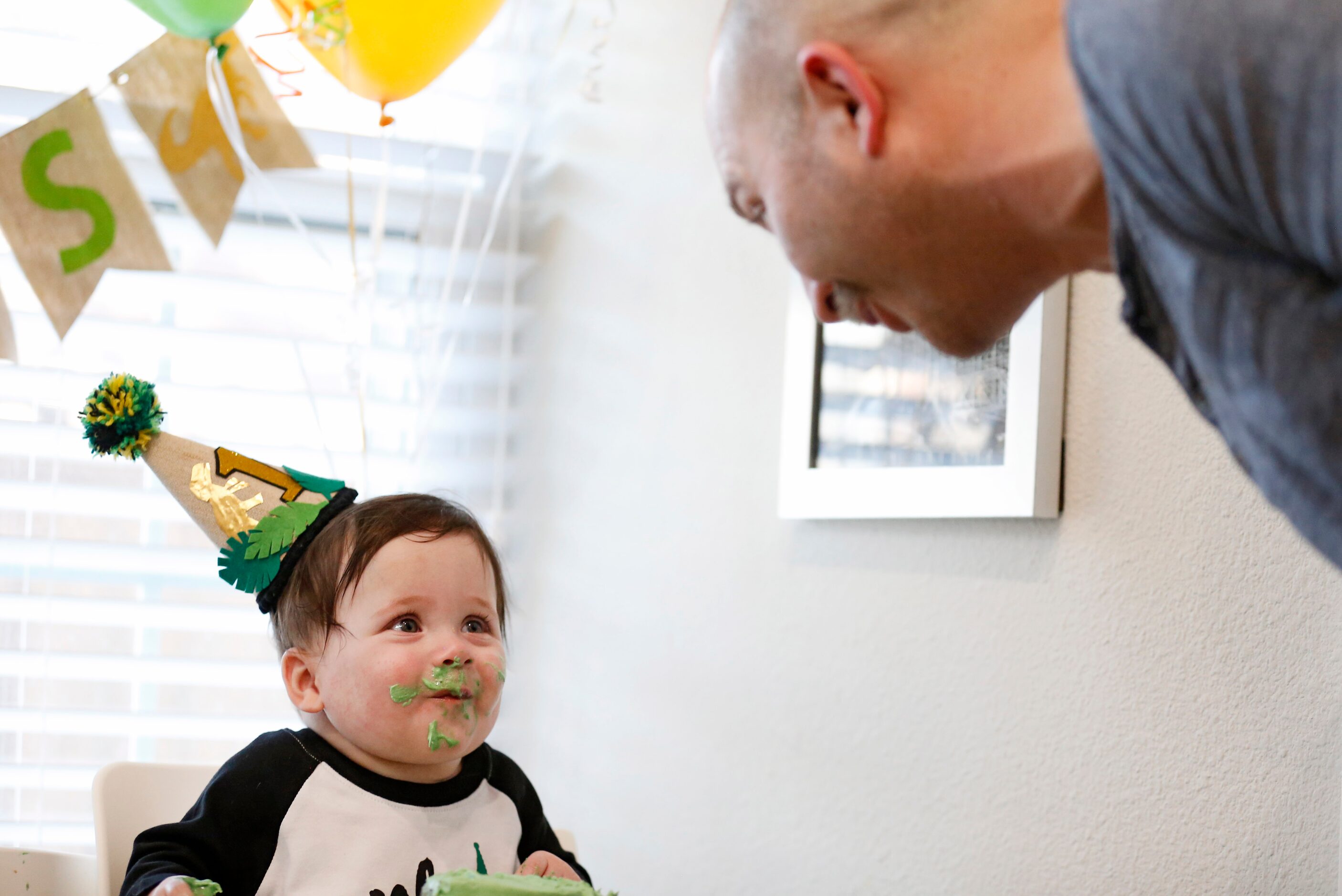 Hudson Marr looks at his father Chris Marr while eating cake during his one year birthday...