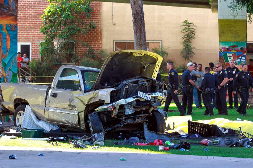 Police stand near the pickup truck that landed at Chicano Park after it flew off a ramp to...