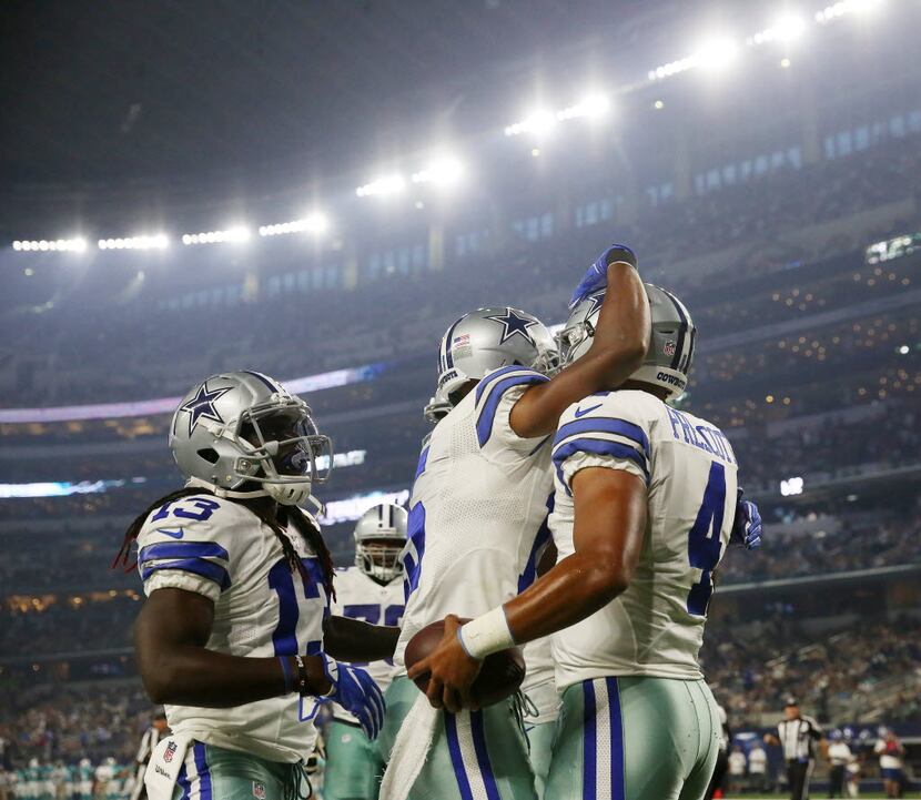 Dallas Cowboys teammates celebrate with quarterback Dak Prescott (4) after Prescott scored a...