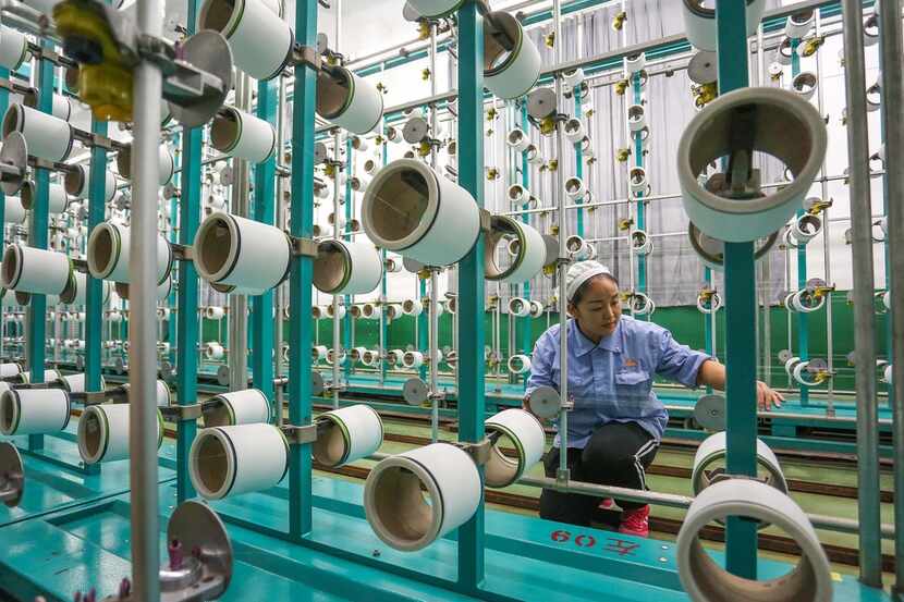 This photo taken on November 22, 2018 shows a worker checking equipment at a textile factory...
