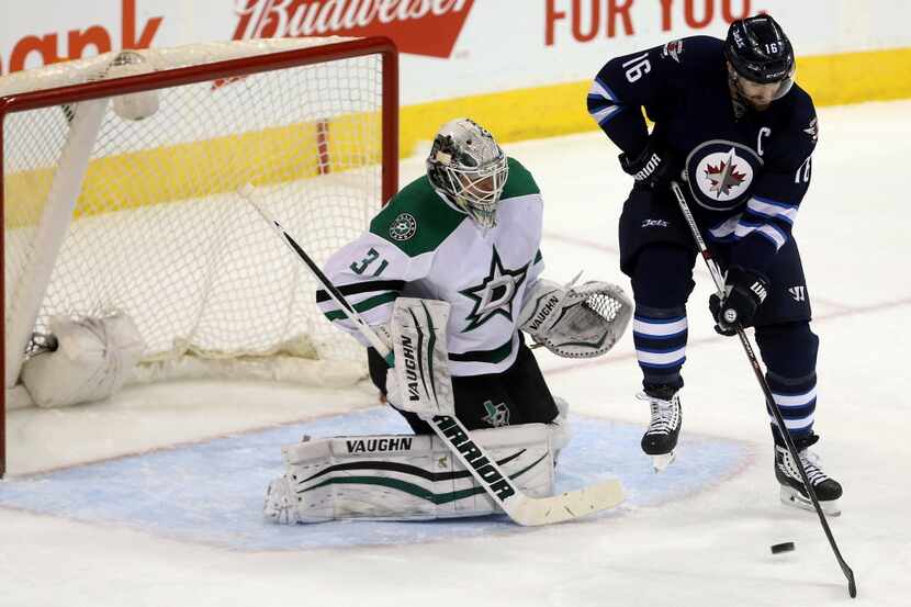 Winnipeg Jets' Andrew Ladd (16) tries to deflect a shot past Dallas Stars goaltender Antti...