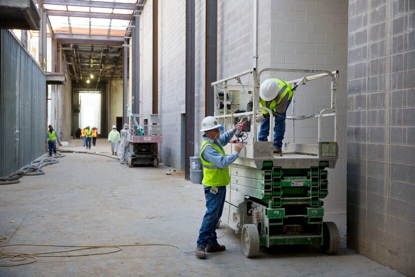 Jose Lopez (right) hands equipment to Gary Walke as they work on the new Memorial High...