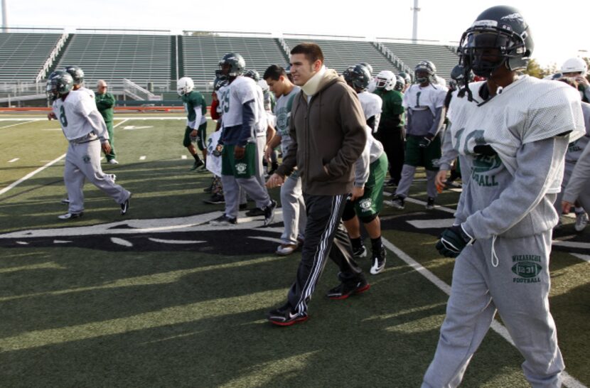 Wearning a neck brace, Triston Simpler (center) walks off the field with teammates after a...