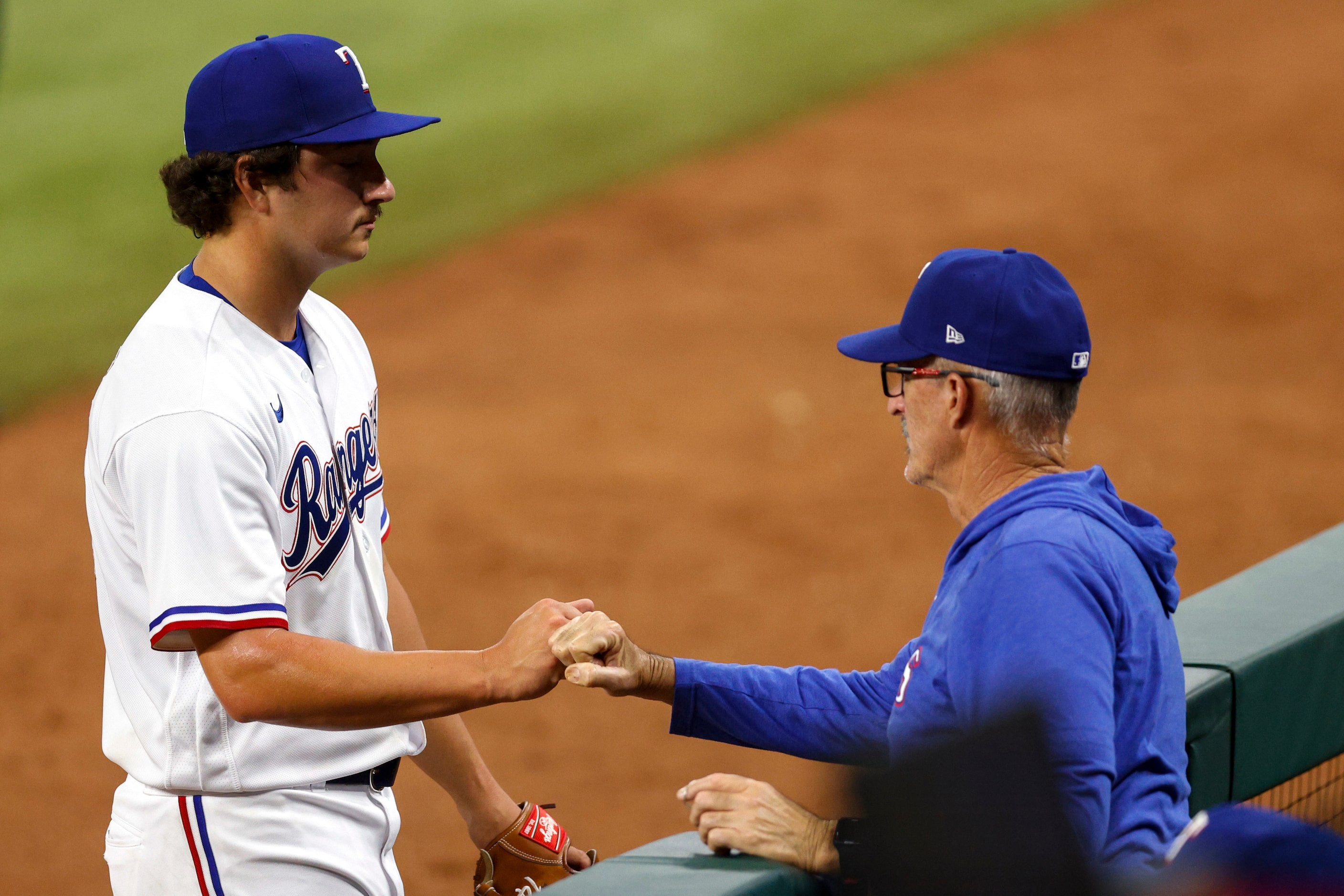 Texas Rangers relief pitcher Owen White (43) fist bumps pitching coach Mike Maddux (31)...