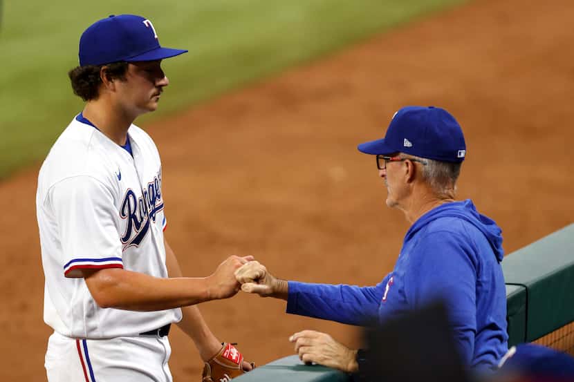 Texas Rangers relief pitcher Owen White (43) fist bumps pitching coach Mike Maddux (31)...