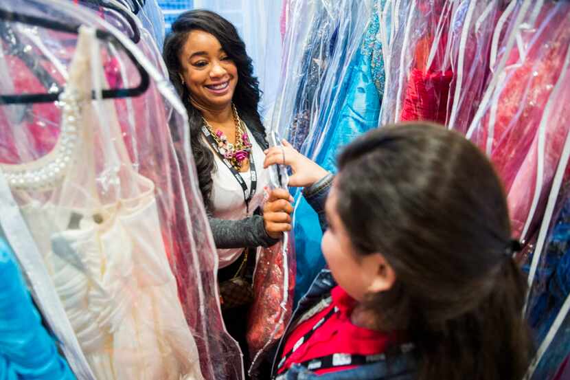 Consultant Nyesha Anglin (left) hands a prom dress to Justin F. Kimball High School student...