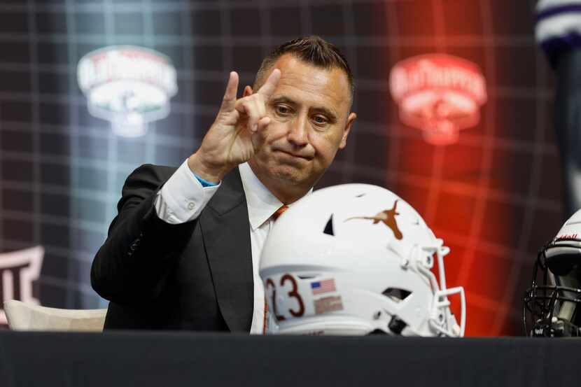 Texas head coach Steve Sarkisian holds up hook’ em horns during the Big 12 Media Days at...