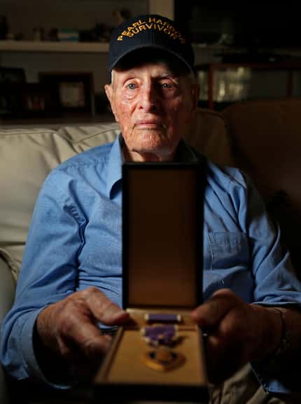 Pearl Harbor survivor John E. Lowe displays his Purple Heart at his son's house in...