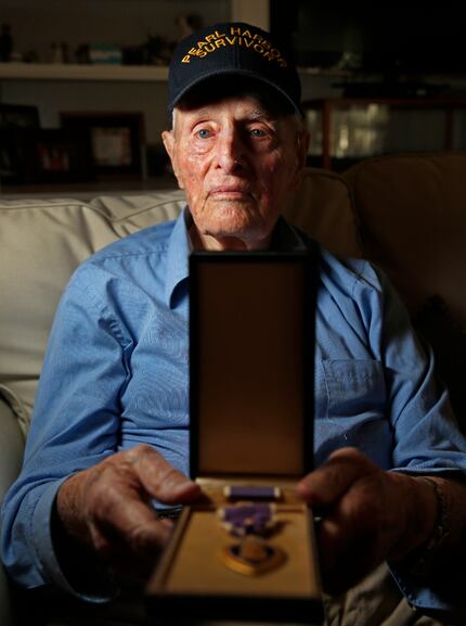 Pearl Harbor survivor John E. Lowe displays his Purple Heart at his son's house in...