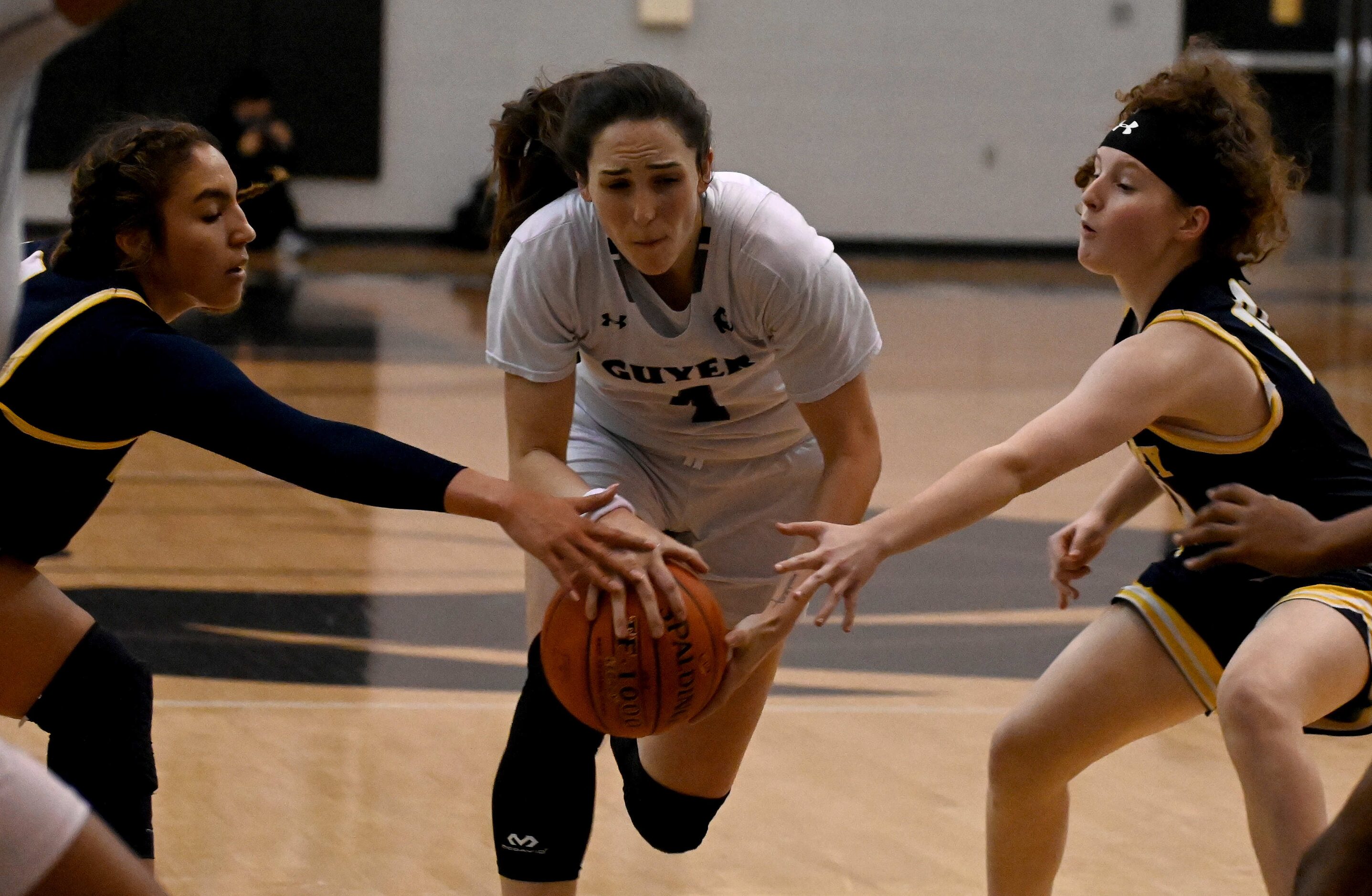 Denton Guyer’s Evie Goetz drives between McKinney’s Trinity White, left, and Emily Barnhill...