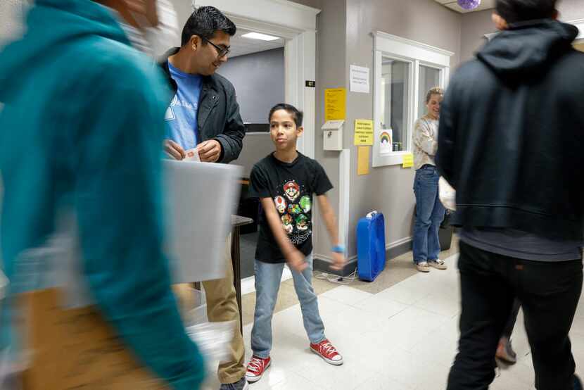 Asher Vargas junto a su padre Luis Vargas recibiendo migrantes en la Oak Lawn United...