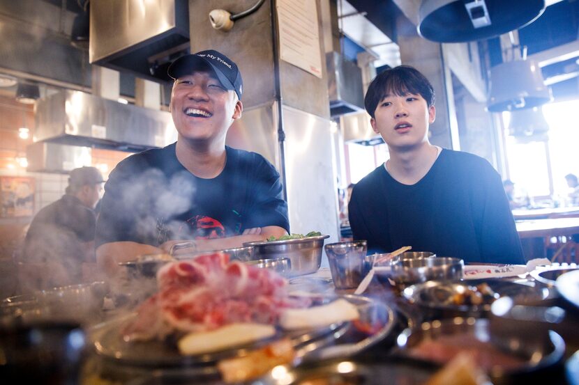 OGE, sitting in Los Angeles' Koreatown, laugs while friend Jeon Kyoung-Min, right, looks on.