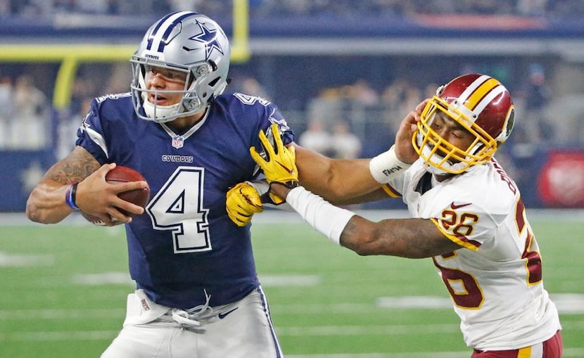 Dallas Cowboys quarterback Dak Prescott (4) stiff-arms Washington cornerback Bashaud...