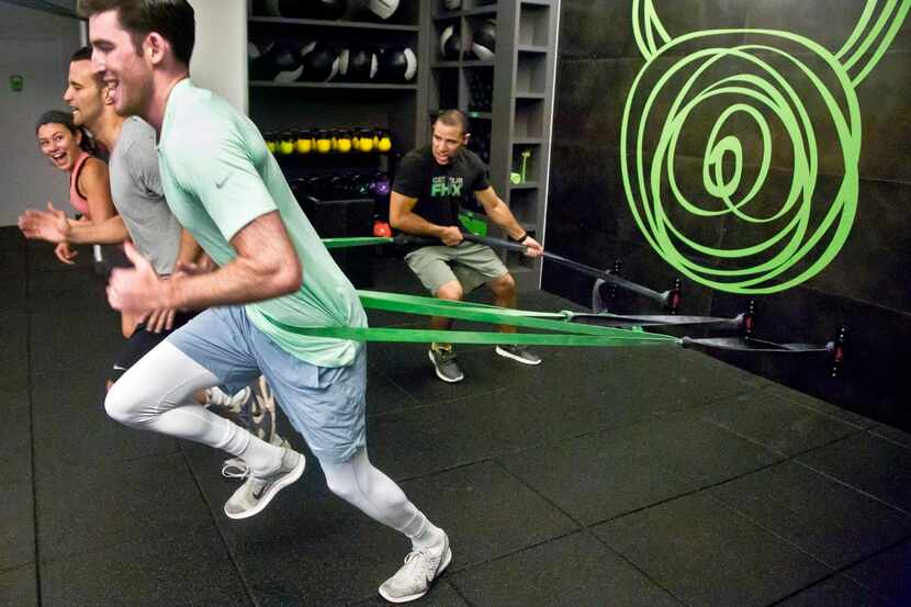 
Gym instructor Javier Martinez (back) has clients run using resistance bands during a...