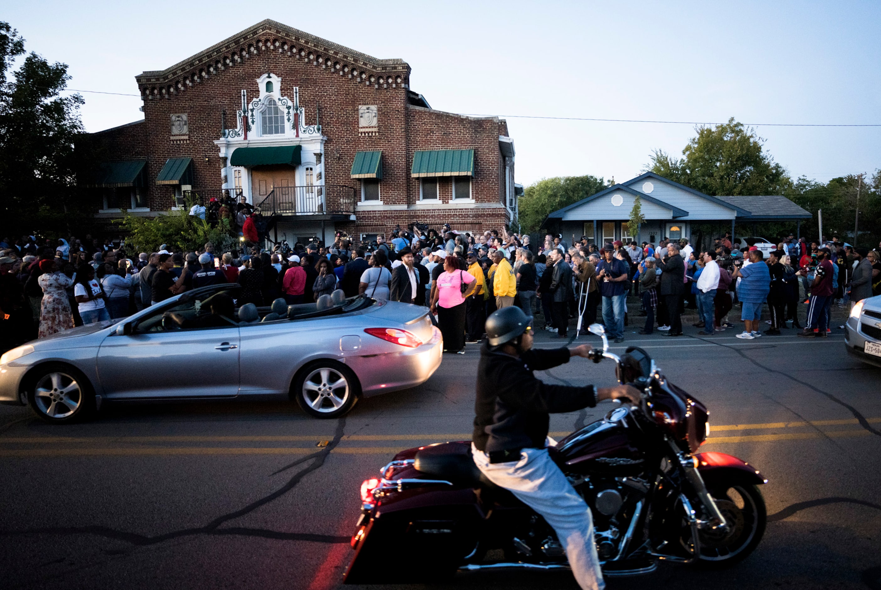 A large crowd of protestors gathers outside the house (right) where Atatiana Jefferson was...