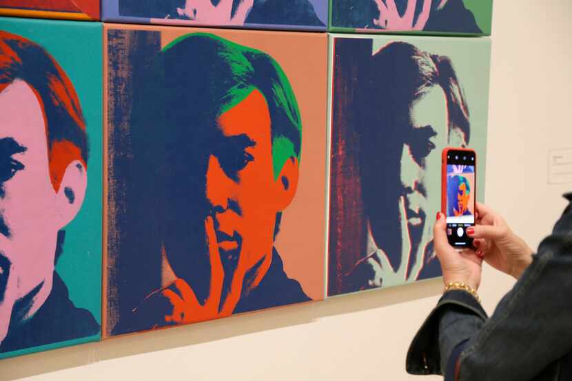 A visitor records one of a series of self portraits at the exhibition "Andy Warhol — From A...