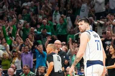 Dallas Mavericks guard Luka Doncic (77) looks back as fans celebrates after a 3-pointer by...