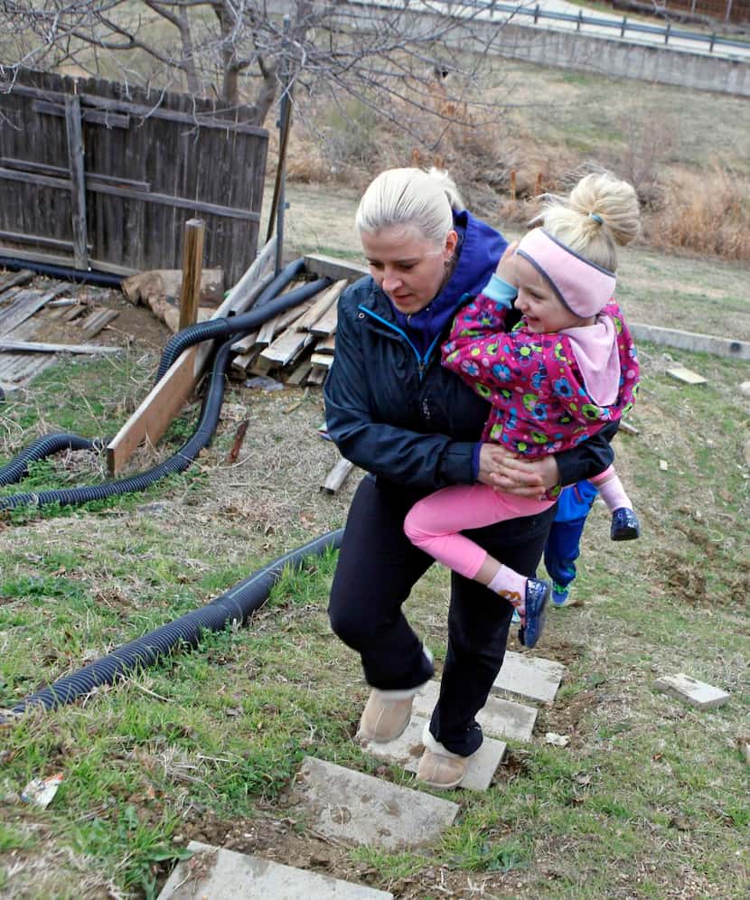 
Petra Chudejova carries her daughter, Helenn, 6, as she walks on cinderblock steps her...