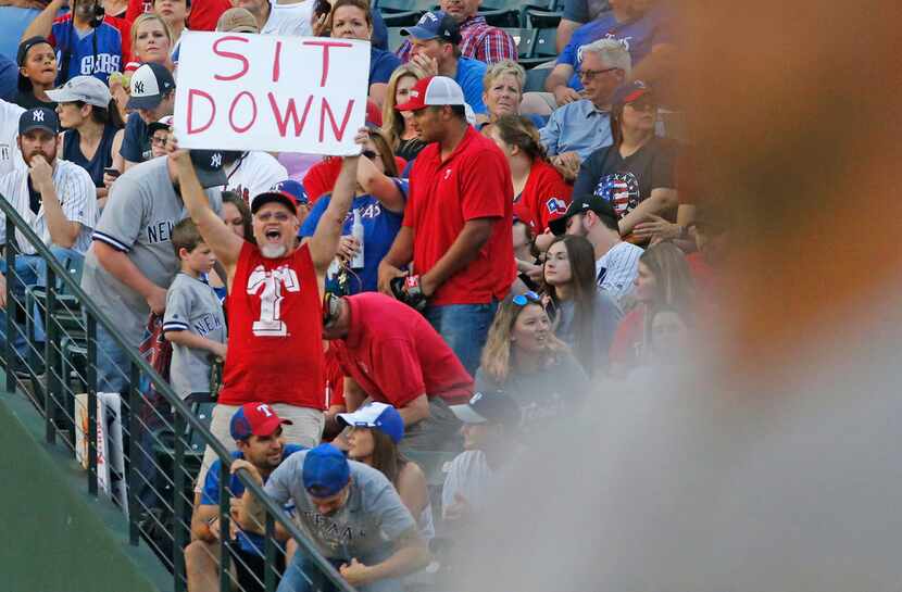 A Rangers fan tries expresses himself from the right field stands in foul ground during the...