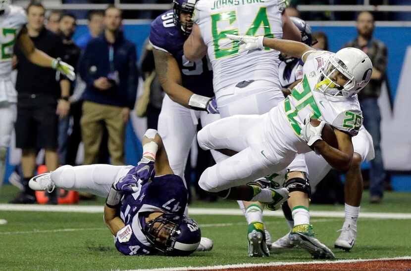 Oregon running back Tony Brooks-James (20) breaks the grasp of TCU defensive end Tipa Galeai...