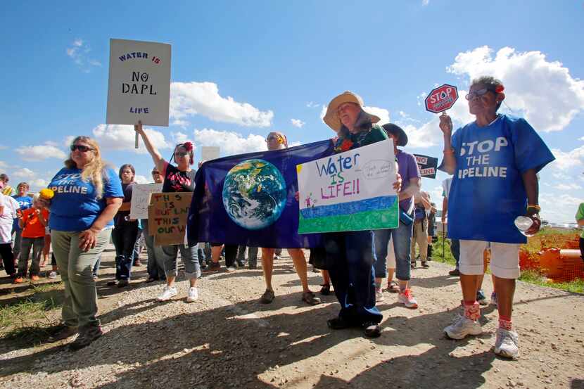 A group of people hold signs as they prepare to trespass into a Dakota Access Pipeline...