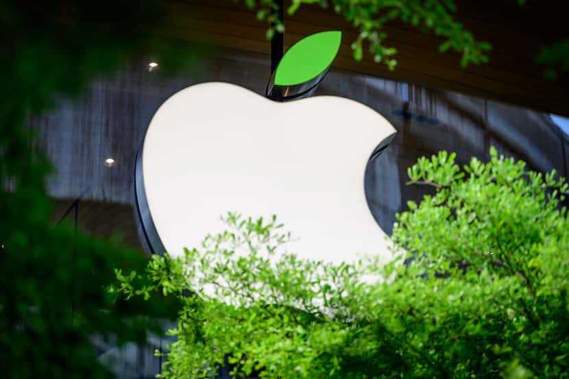 The Apple logo sporting a green leaf to mark the upcoming Earth Day is seen on a window of...