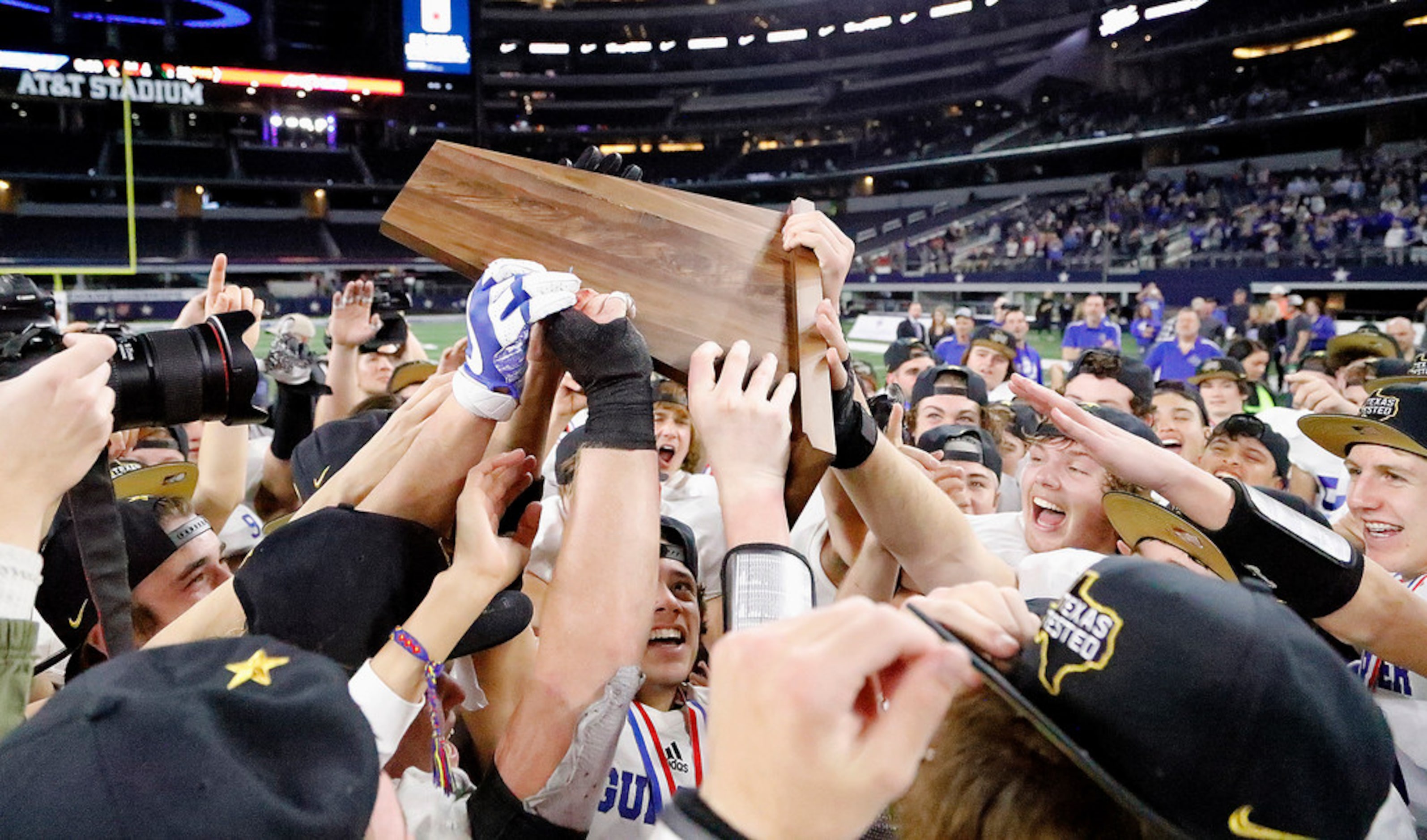 The Gunter High School football team celebrates with the championship trophy after their...