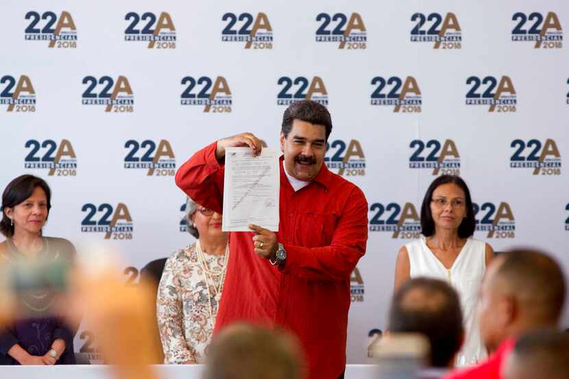 El presidente venezolano Nicolás Maduro presenta un certificado que formaliza su candidatura...