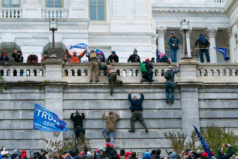 Supporters of former President Donald Trump climb the west wall of the the U.S. Capitol in...