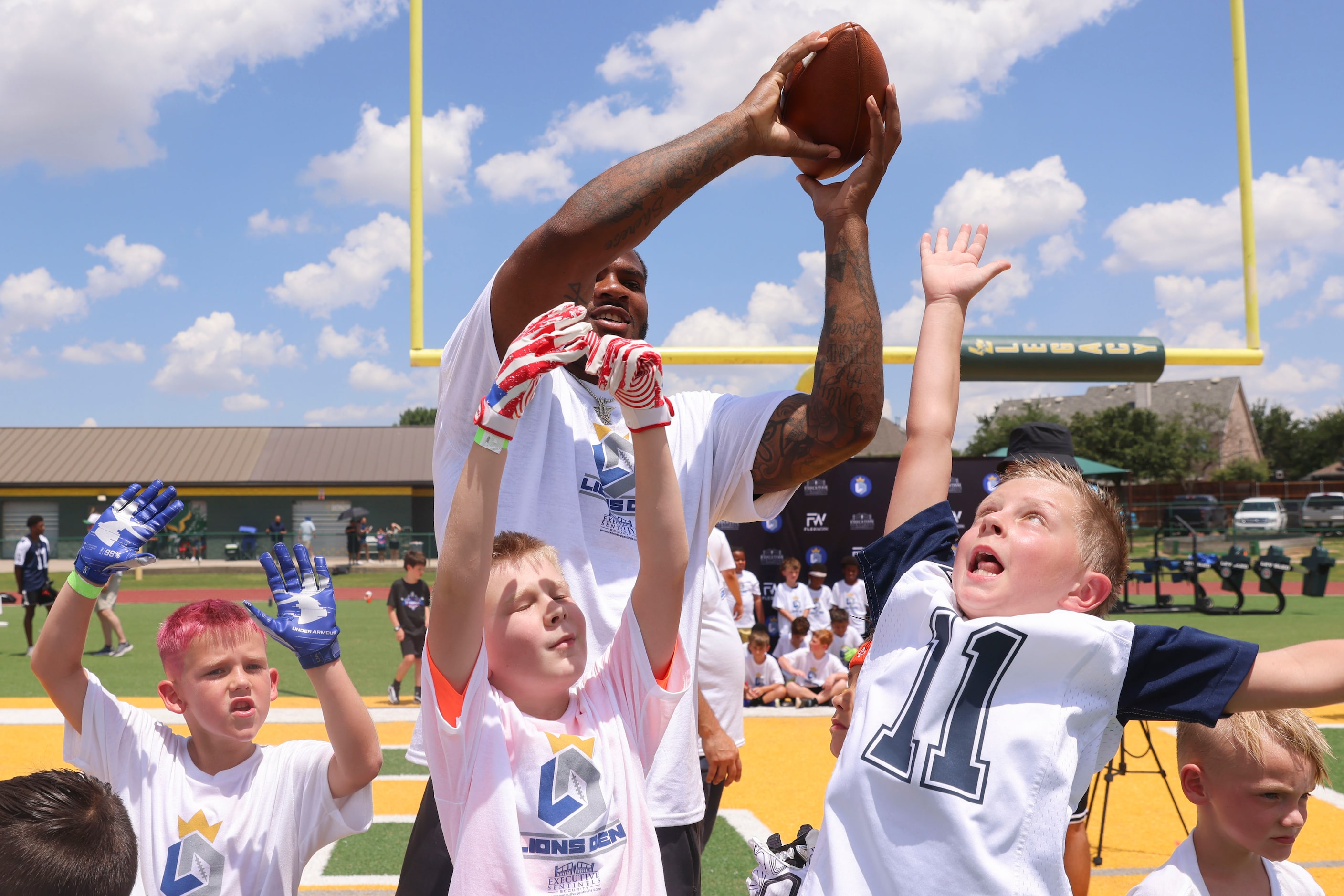 Dallas Cowboys linebacker Micah Parsons receives a pass as he interacts with young football...