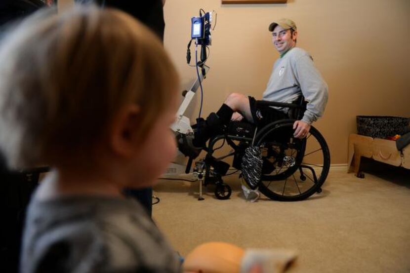 
Garland firefighter Devon Colbert looks over at his son, Deagan, while he does therapy on a...